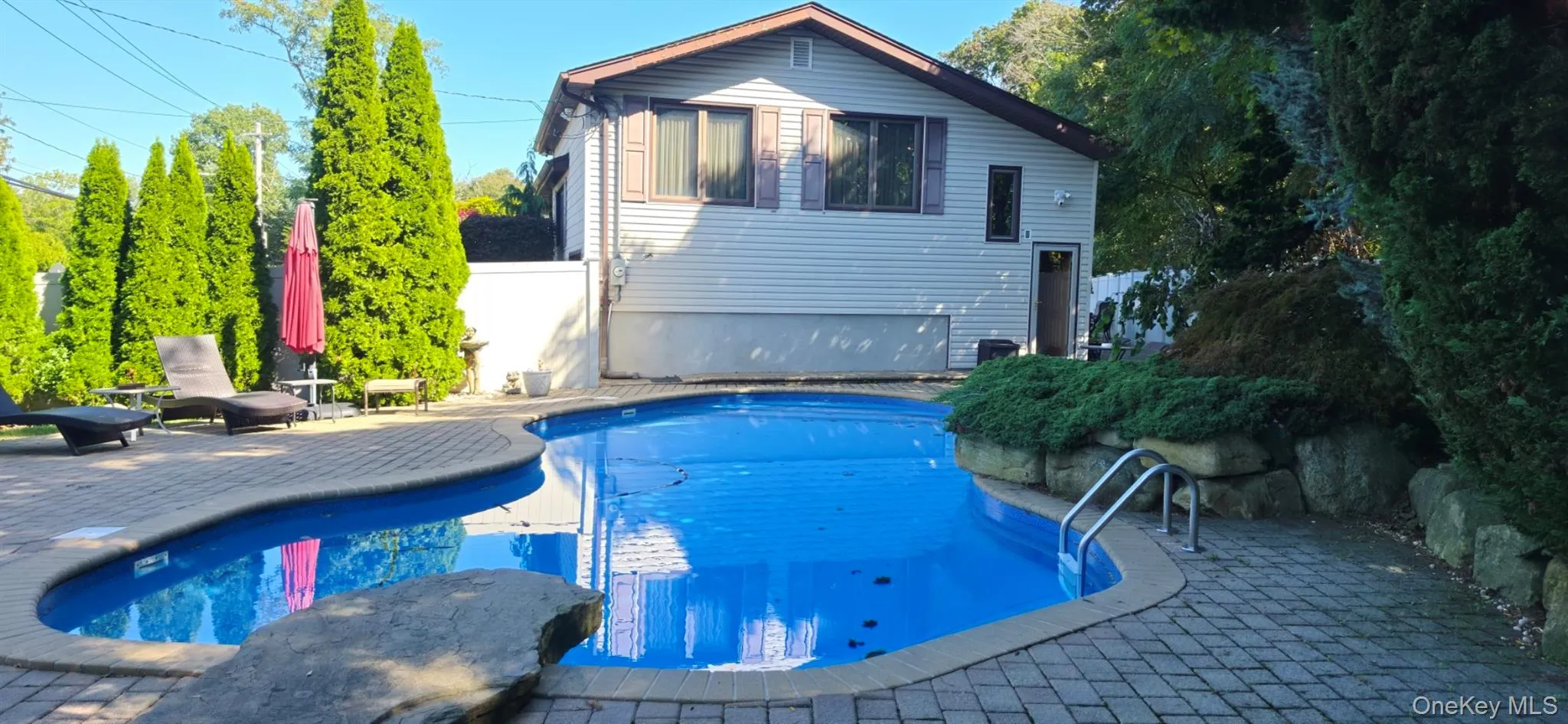 Kidney-shaped swimming pool with a protective cover, surrounded by a paver patio Kidney-shaped swimming pool with a protective cover, surrounded by a paver patio