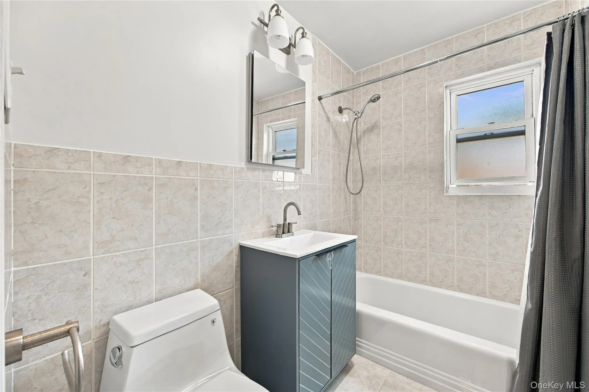 Tiled bathroom with new toilet, vanity, medicine cabinet, light fixture, and reglazed bathtub. Tiled bathroom with new toilet, vanity, medicine cabinet, light fixture, and reglazed bathtub.