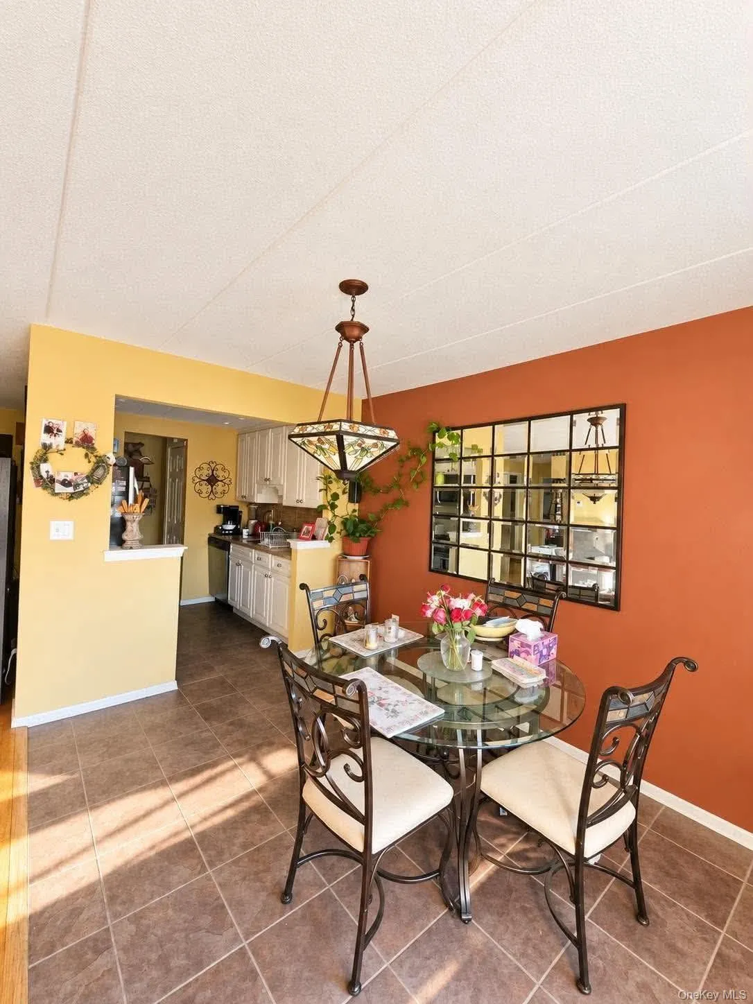 Tiled flooring extends through the dining area and kitchen, featuring a decorative ceiling light fixture Tiled flooring extends through the dining area and kitchen, featuring a decorative ceiling light fixture