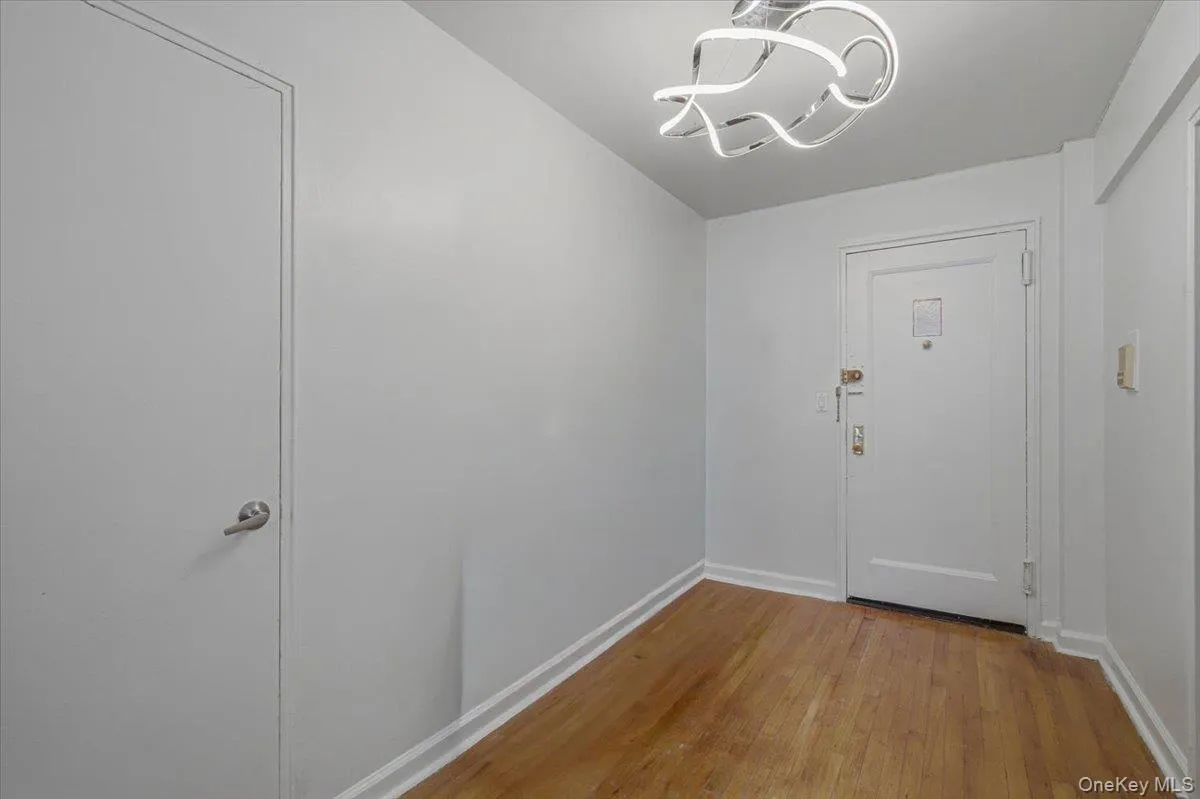 Wood-finish flooring, white doors, and a modern ceiling light fixture Wood-finish flooring, white doors, and a modern ceiling light fixture