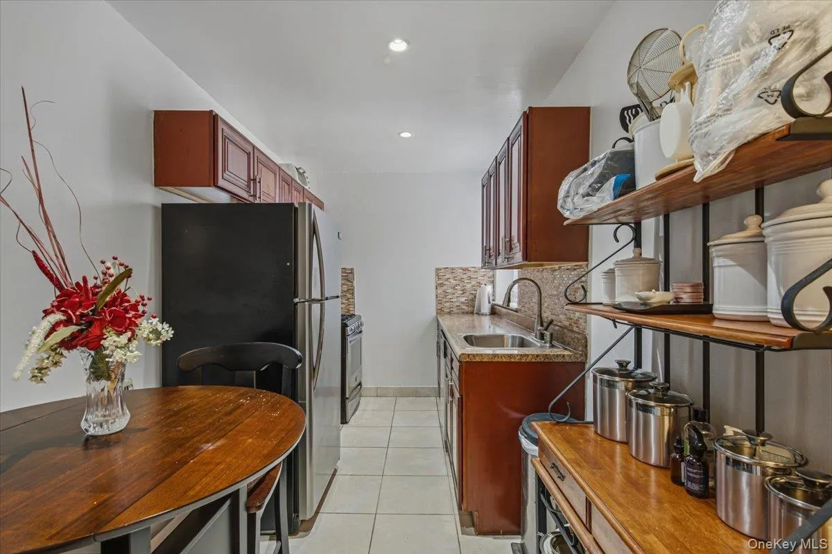 Galley kitchen with brown cabinetry, recessed lighting, and a mosaic tile backsplash Galley kitchen with brown cabinetry, recessed lighting, and a mosaic tile backsplash