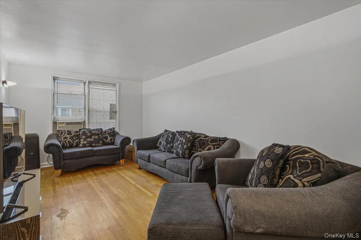 Hardwood flooring throughout, window unit air conditioning, and a wall-mounted light fixture Hardwood flooring throughout, window unit air conditioning, and a wall-mounted light fixture