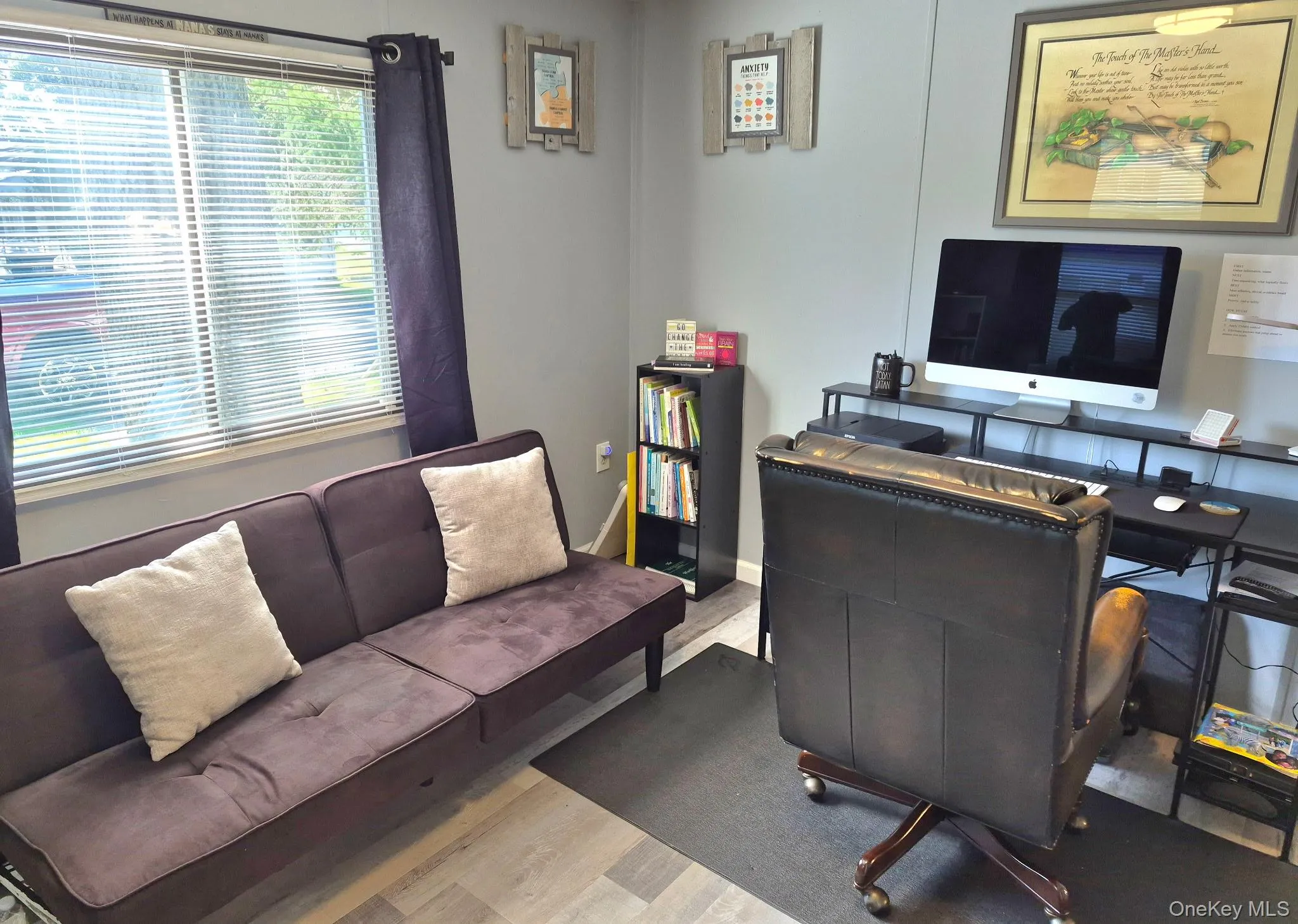 Light gray wall paint, window with horizontal blinds, wood-finish flooring, and a black built-in shelving unit Light gray wall paint, window with horizontal blinds, wood-finish flooring, and a black built-in shelving unit