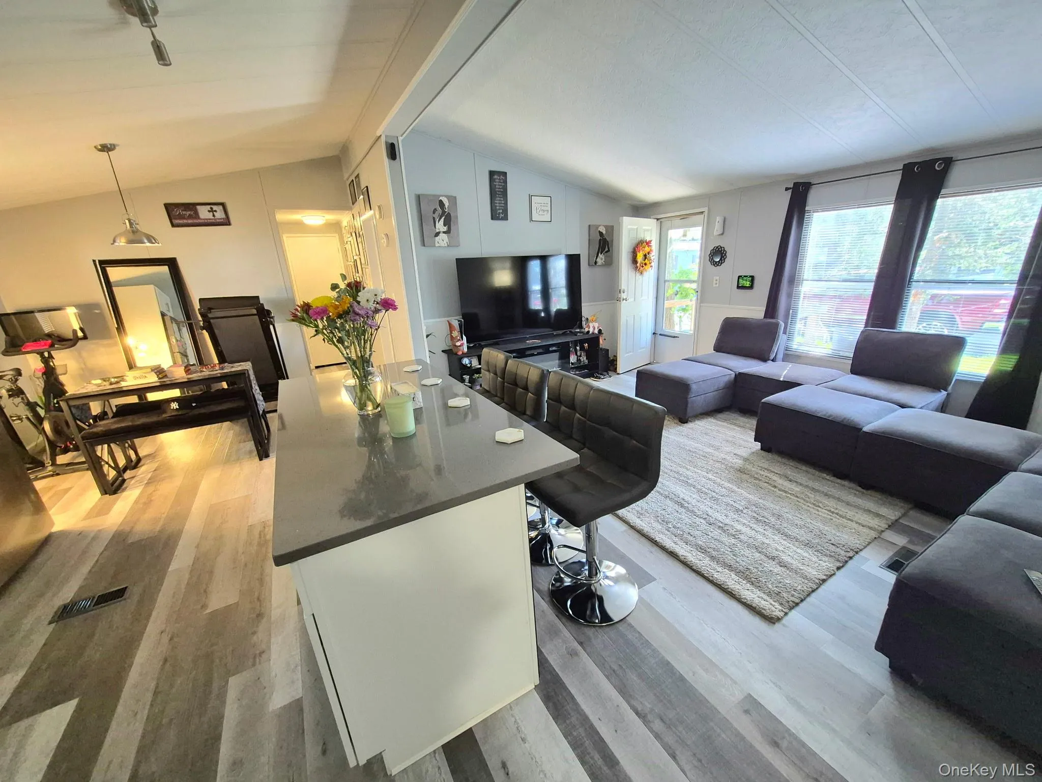 Vaulted ceilings, wood-finish flooring, and a kitchen island with seating Vaulted ceilings, wood-finish flooring, and a kitchen island with seating