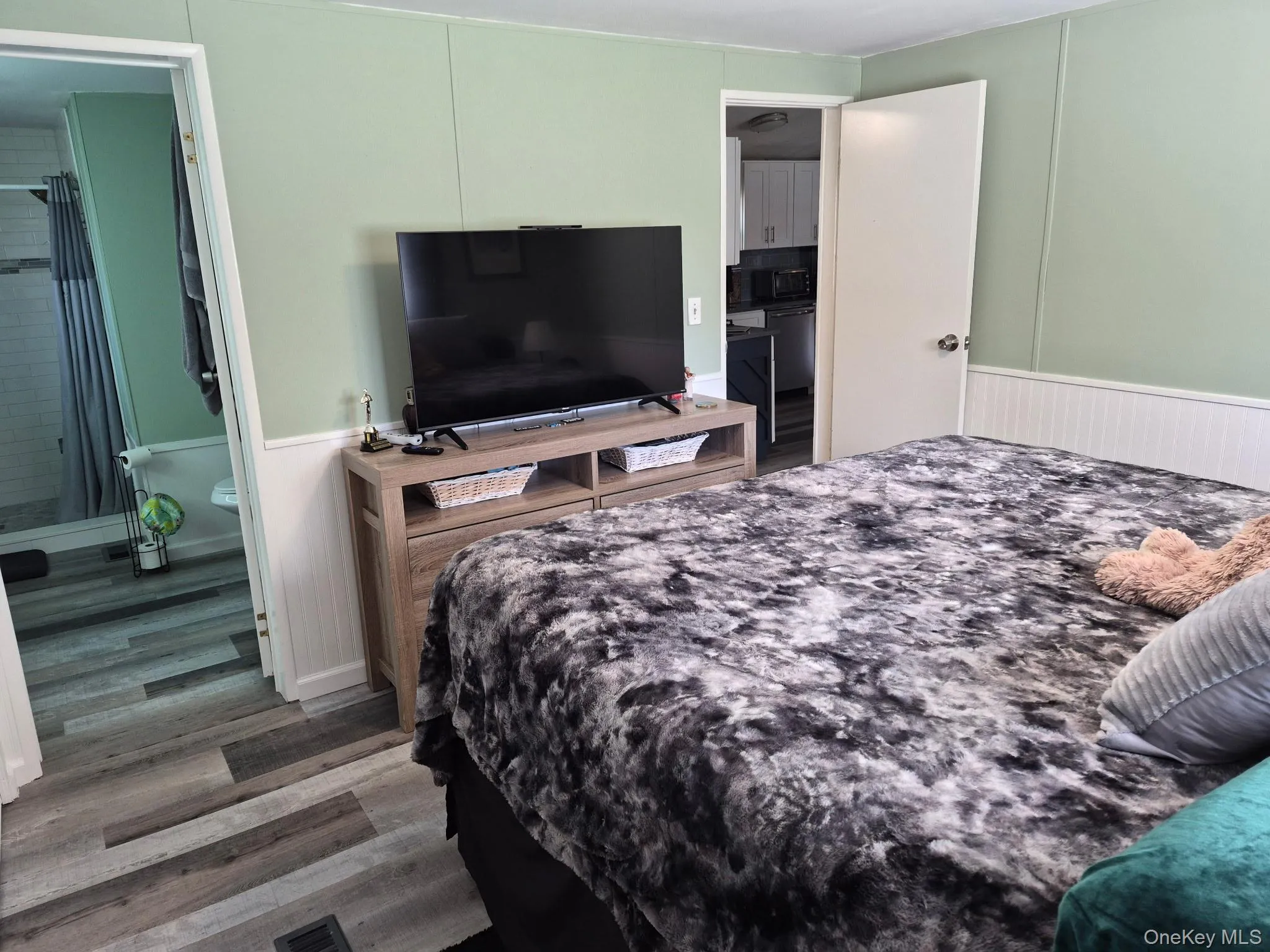 Wood-finish flooring, light green wall paneling, white wainscoting, and white trim throughout Wood-finish flooring, light green wall paneling, white wainscoting, and white trim throughout