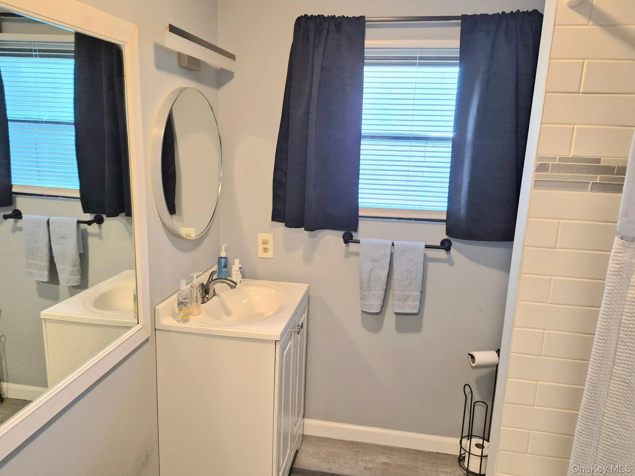 White vanity with integrated sink, brushed nickel faucet, and oval wall mirror White vanity with integrated sink, brushed nickel faucet, and oval wall mirror