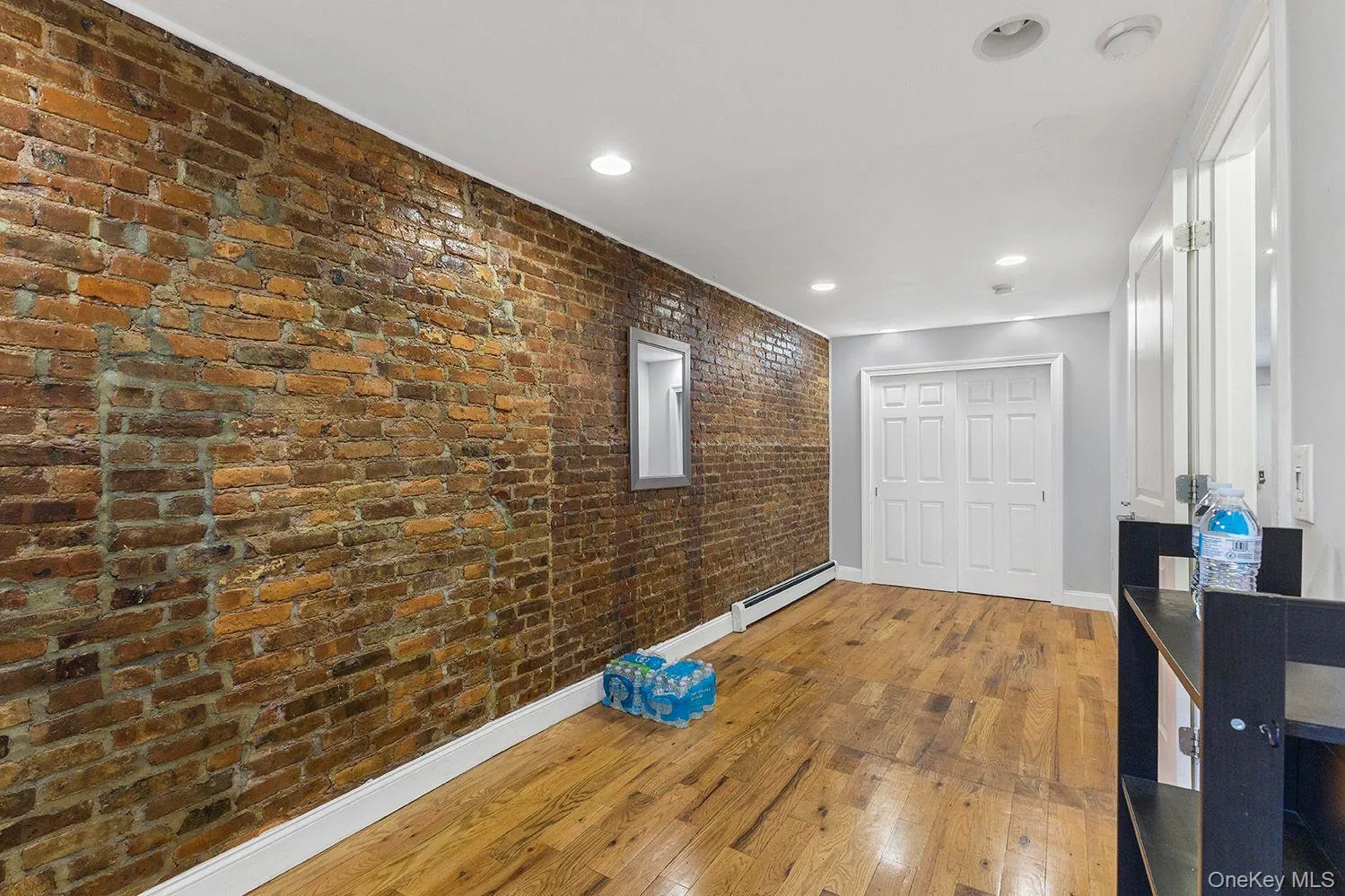Bedroom with exposed brick accent wall, wood-finish flooring, recessed ceiling lighting Bedroom with exposed brick accent wall, wood-finish flooring, recessed ceiling lighting