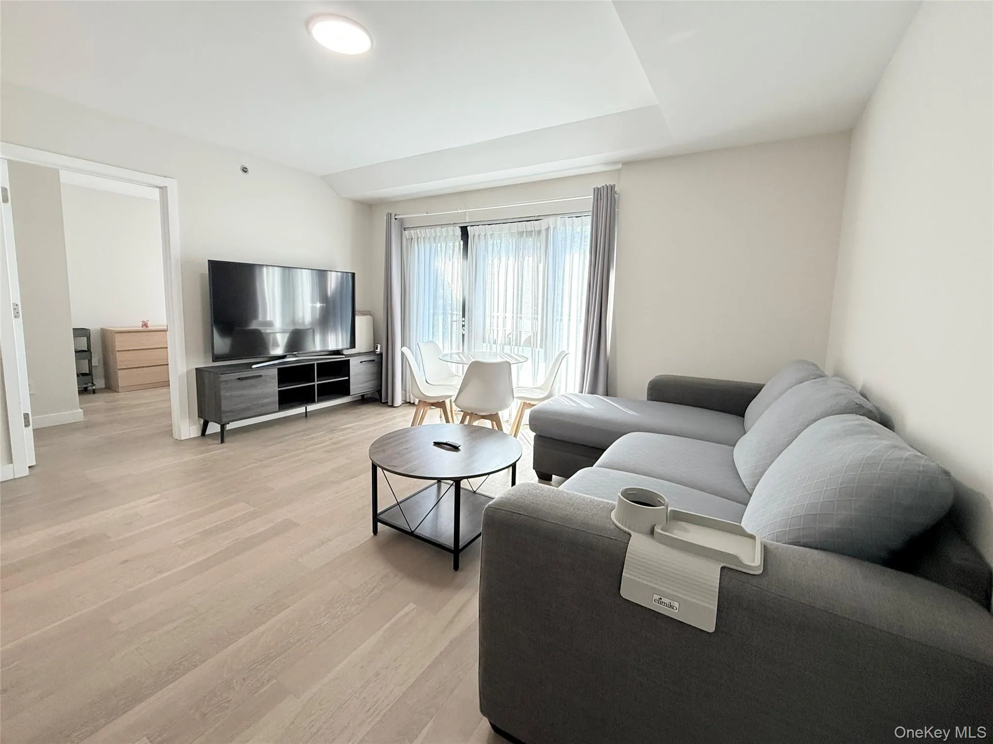 Light wood-finish flooring throughout, recessed ceiling lighting, and a sliding glass door with window treatments Light wood-finish flooring throughout, recessed ceiling lighting, and a sliding glass door with window treatments