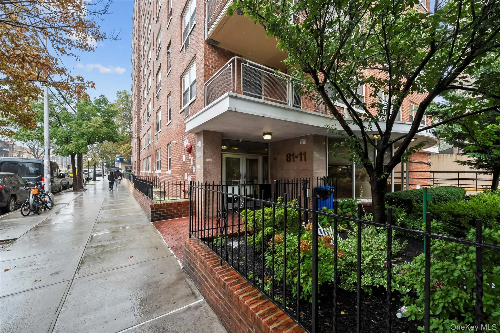 Brick exterior building with prominent signage, featuring balconies with metal railings, a paved sidewalk, and established perimeter landscaping Brick exterior building with prominent signage, featuring balconies with metal railings, a paved sidewalk, and established perimeter landscaping
