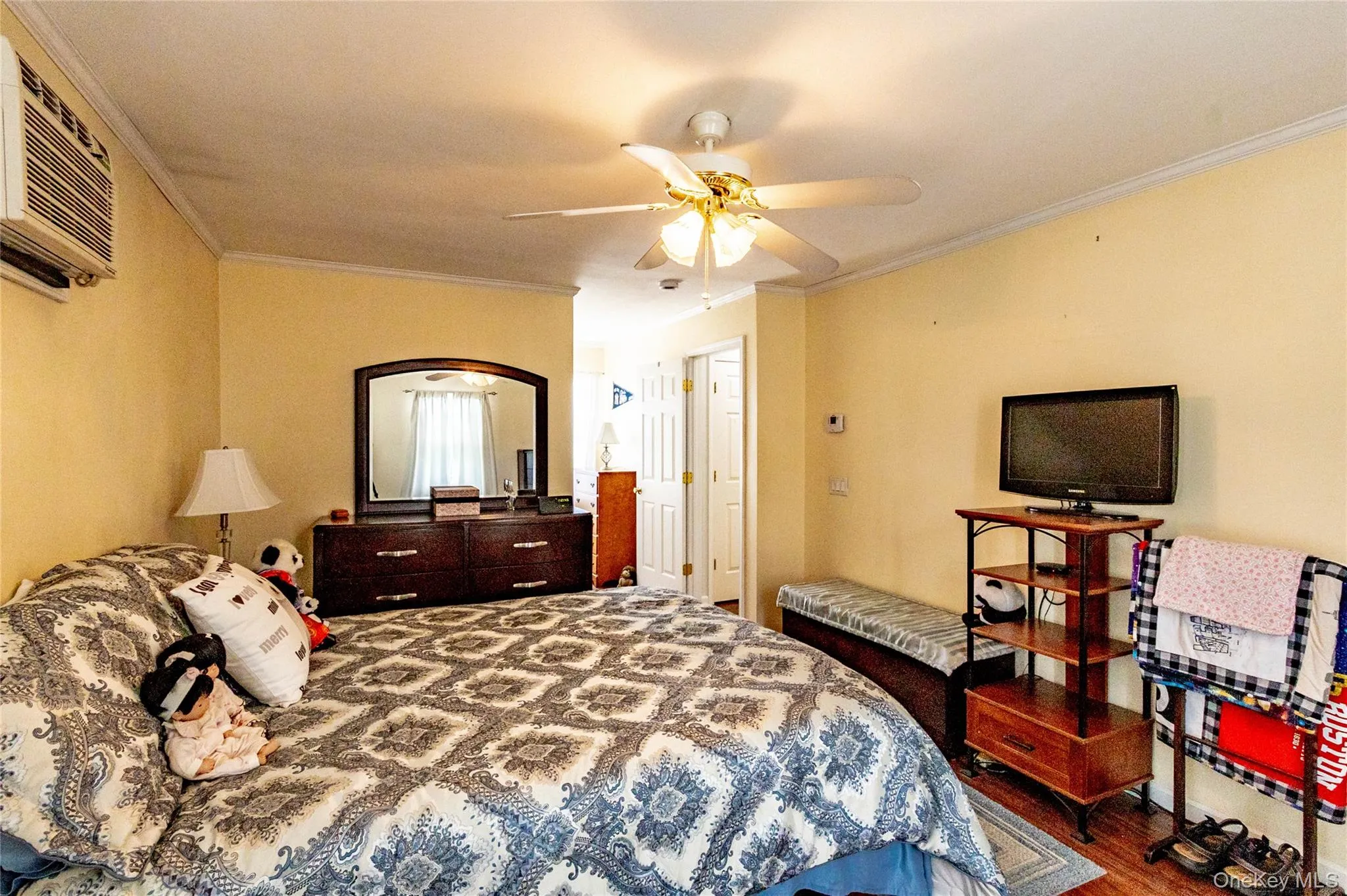 Wall-mounted air conditioning unit, ceiling fan with integrated lighting, and wood-finish flooring Wall-mounted air conditioning unit, ceiling fan with integrated lighting, and wood-finish flooring