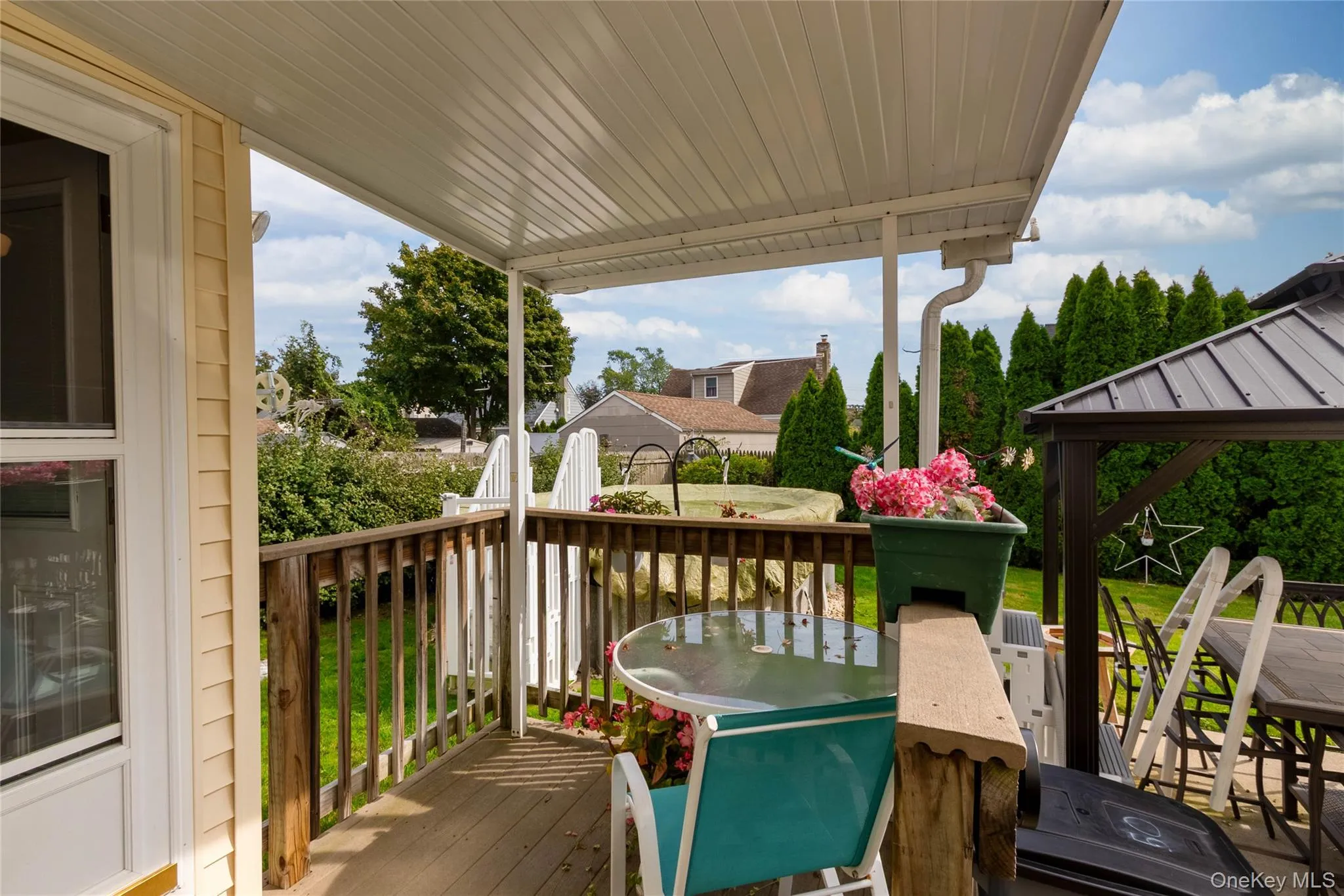 Covered wooden deck with a privacy railing and surrounding manicured lawn Covered wooden deck with a privacy railing and surrounding manicured lawn