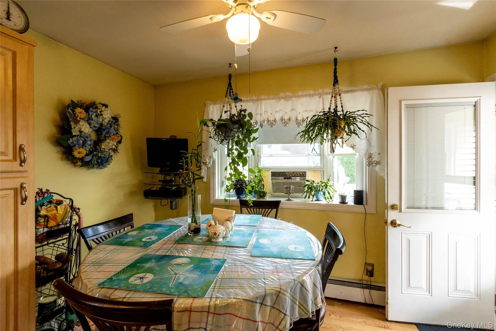 Recessed window with an air conditioning unit, ceiling fan with integrated lighting, wood-finish flooring, and a paneled door with a glass insert Recessed window with an air conditioning unit, ceiling fan with integrated lighting, wood-finish flooring, and a paneled door with a glass insert