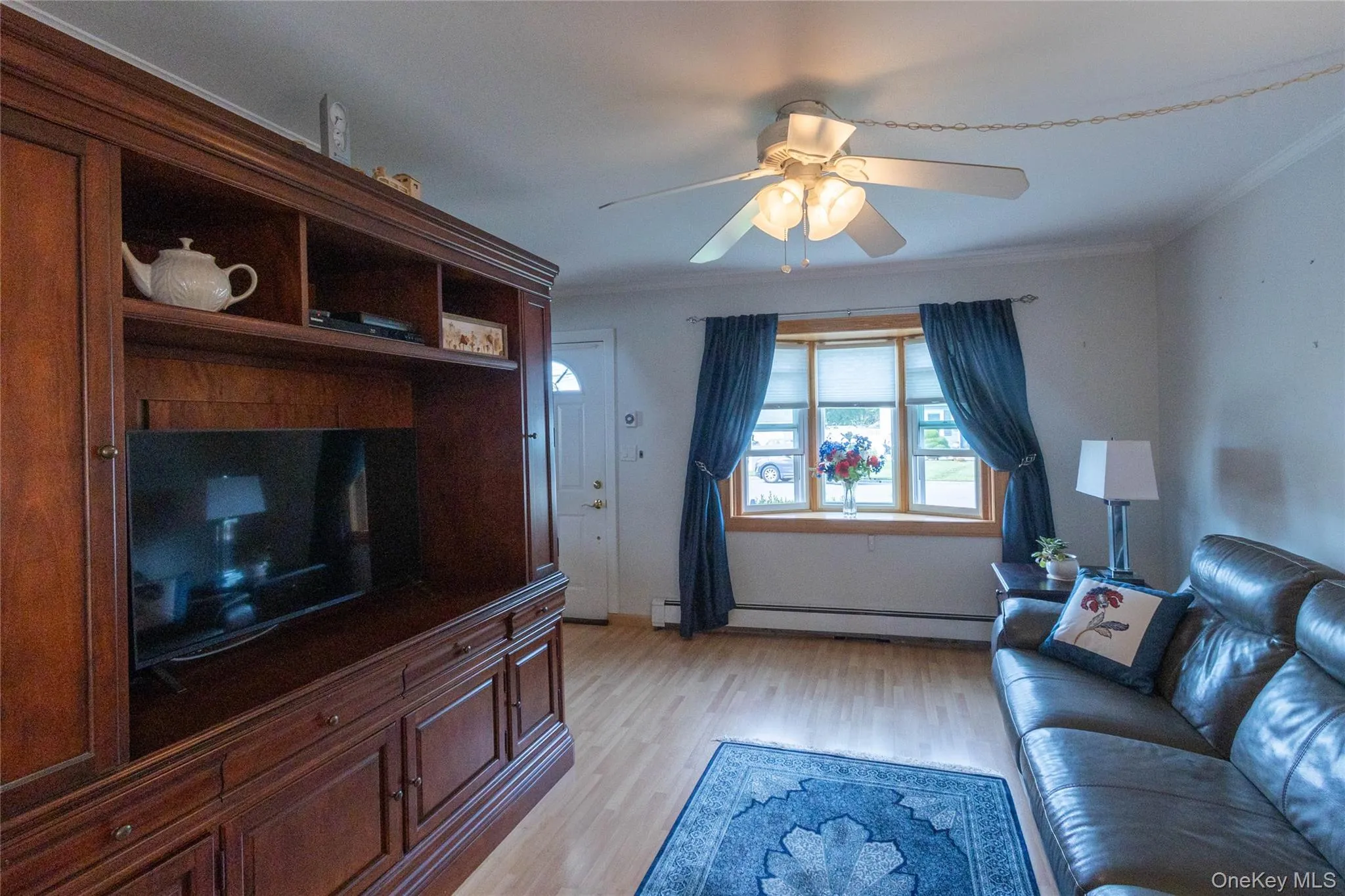 Wood-finish flooring, built-in entertainment center, bay window, ceiling fan, and crown molding Wood-finish flooring, built-in entertainment center, bay window, ceiling fan, and crown molding