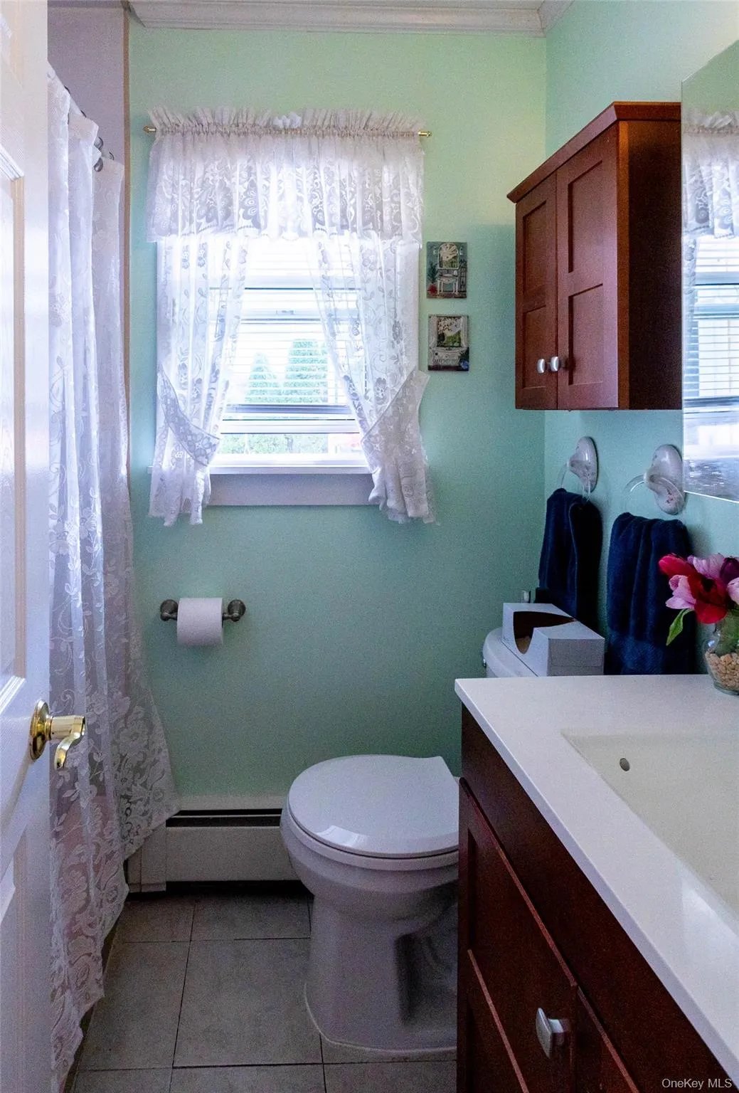 Bathroom featuring a vanity with an integrated sink, a wall-mounted cabinet, and tiled flooring Bathroom featuring a vanity with an integrated sink, a wall-mounted cabinet, and tiled flooring