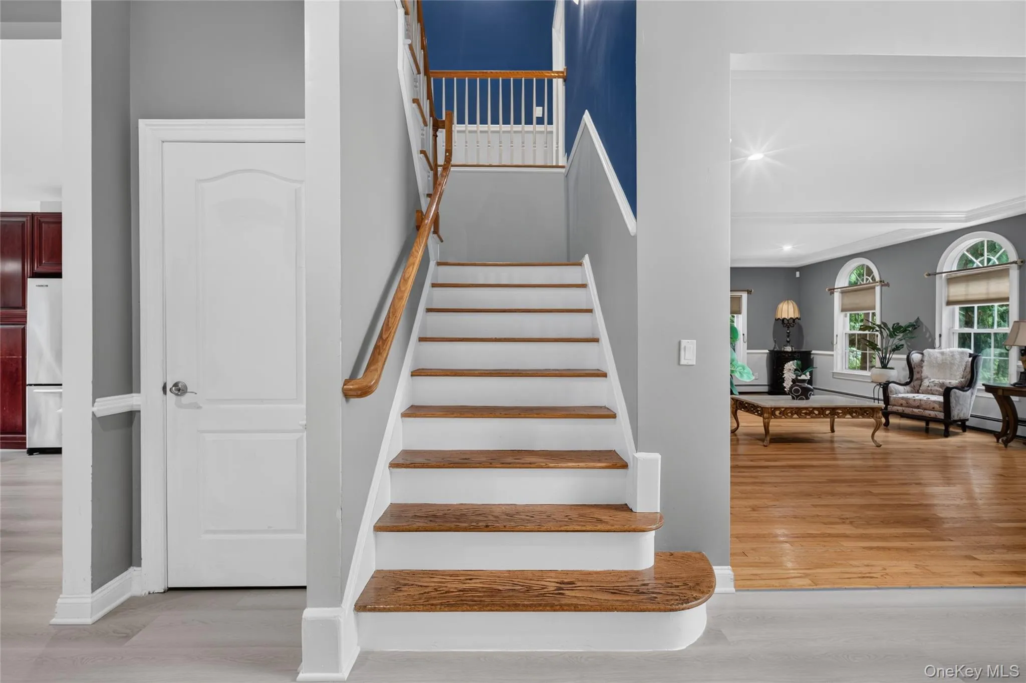 Hardwood staircase with white risers and natural wood treads, white paneled interior door, and light wood-finish flooring Hardwood staircase with white risers and natural wood treads, white paneled interior door, and light wood-finish flooring