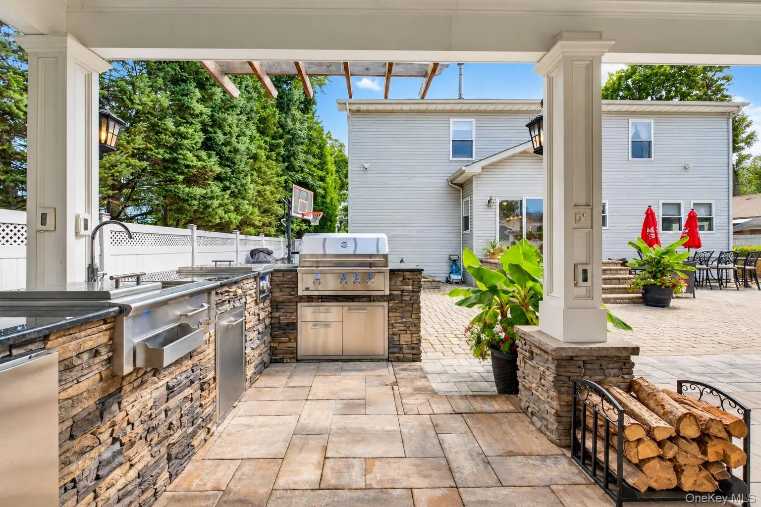 Expansive paver patio with a stone-clad outdoor kitchen, built-in grill, and integrated sink Expansive paver patio with a stone-clad outdoor kitchen, built-in grill, and integrated sink