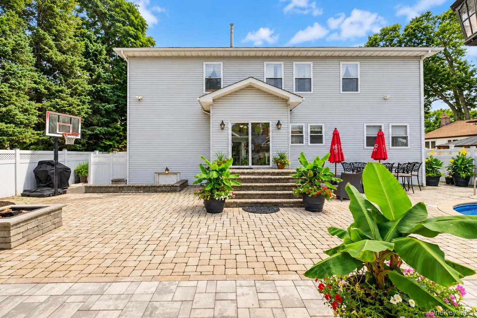 Two-story exterior with light gray siding, paver patio, stone fire pit, and built-in swimming pool Two-story exterior with light gray siding, paver patio, stone fire pit, and built-in swimming pool