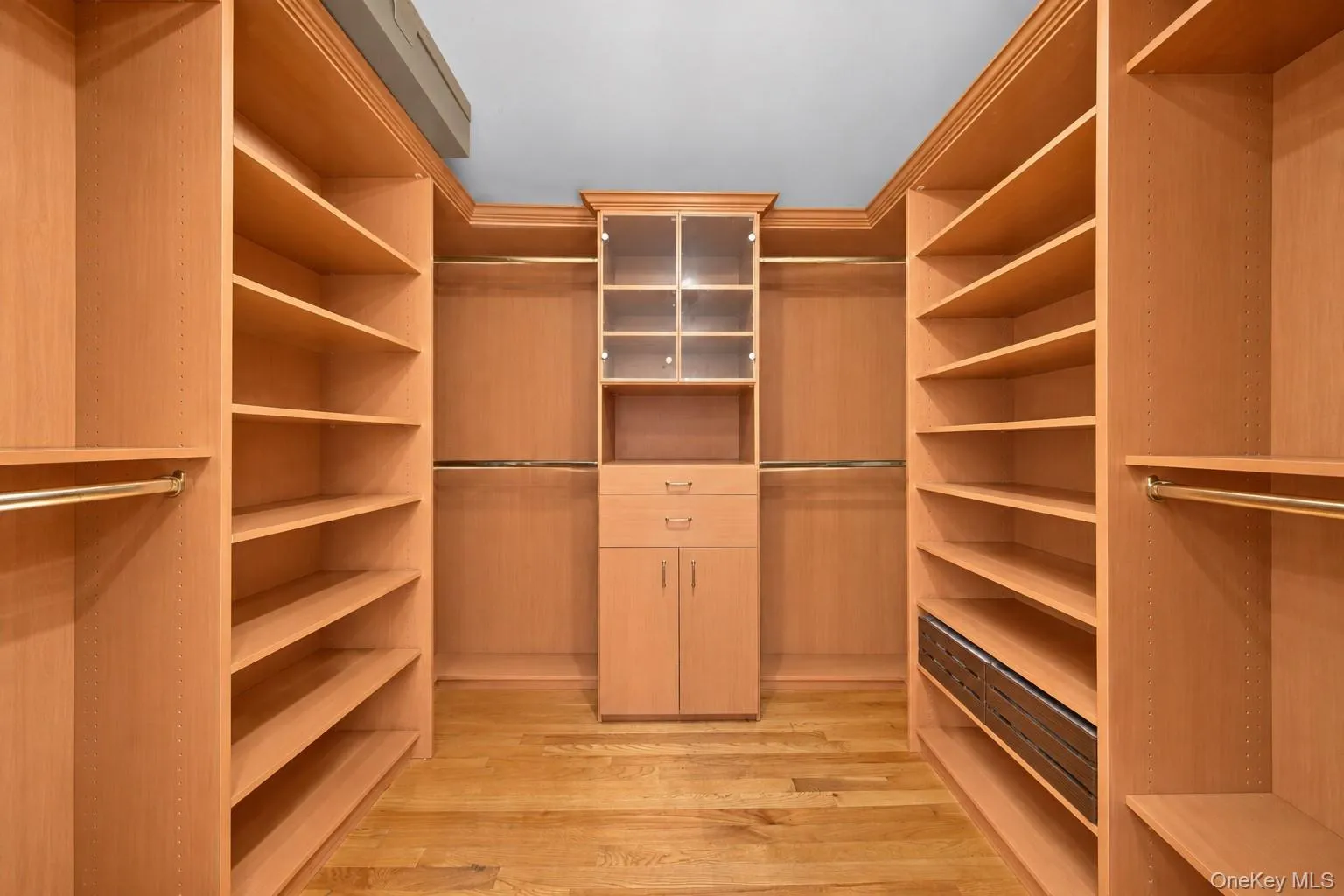 Custom wood-finish cabinetry featuring extensive shelving, hanging rods, and integrated drawers Custom wood-finish cabinetry featuring extensive shelving, hanging rods, and integrated drawers