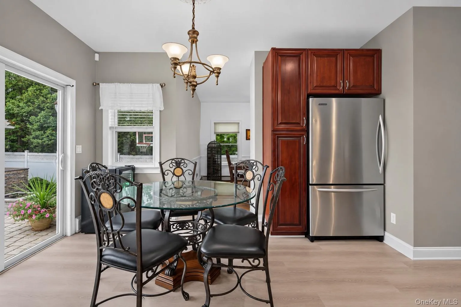 Sliding glass door, wood-finish flooring, stainless steel refrigerator, built-in cabinetry, and ceiling-mounted chandelier Sliding glass door, wood-finish flooring, stainless steel refrigerator, built-in cabinetry, and ceiling-mounted chandelier