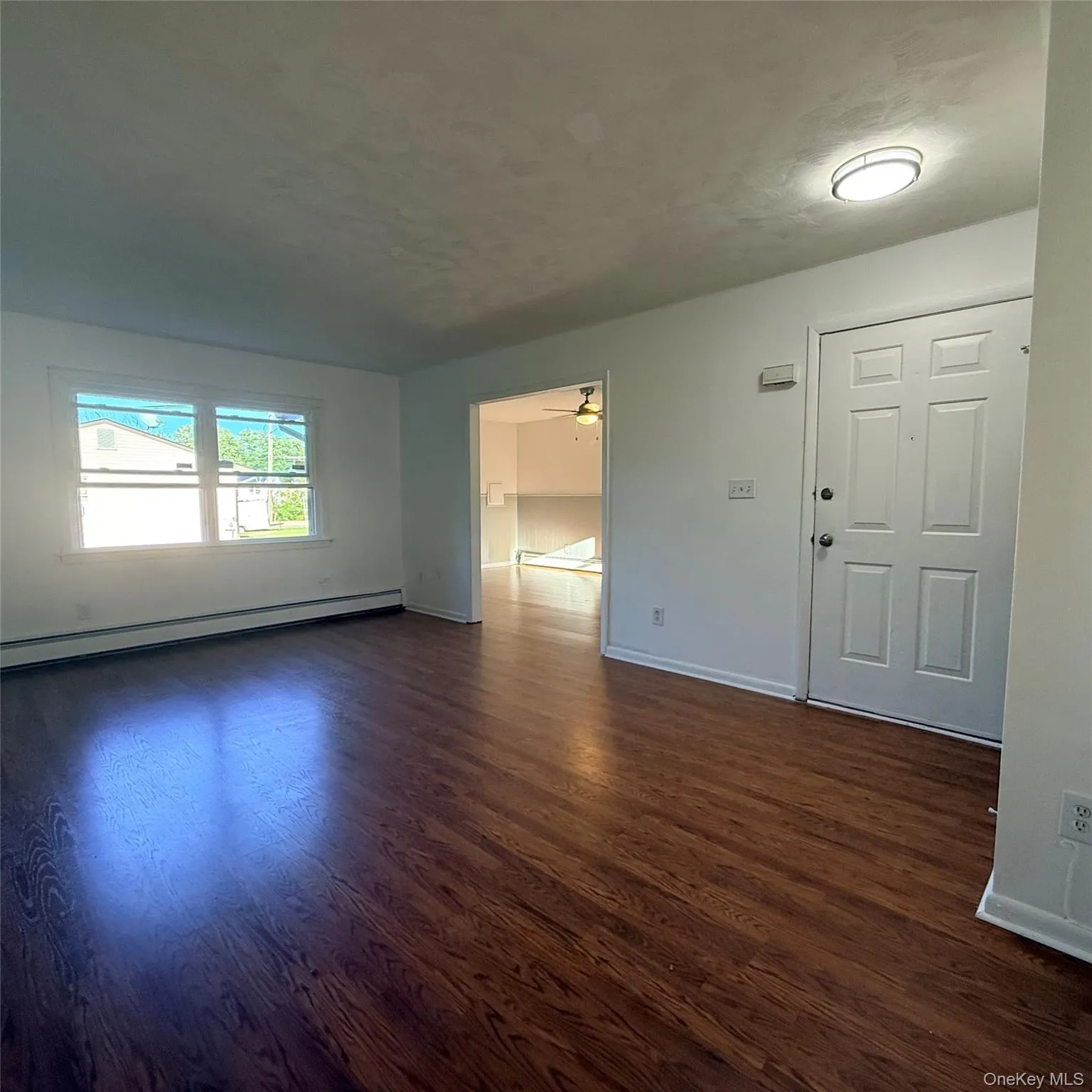 Wood-finish flooring, white walls, and a window with natural light Wood-finish flooring, white walls, and a window with natural light