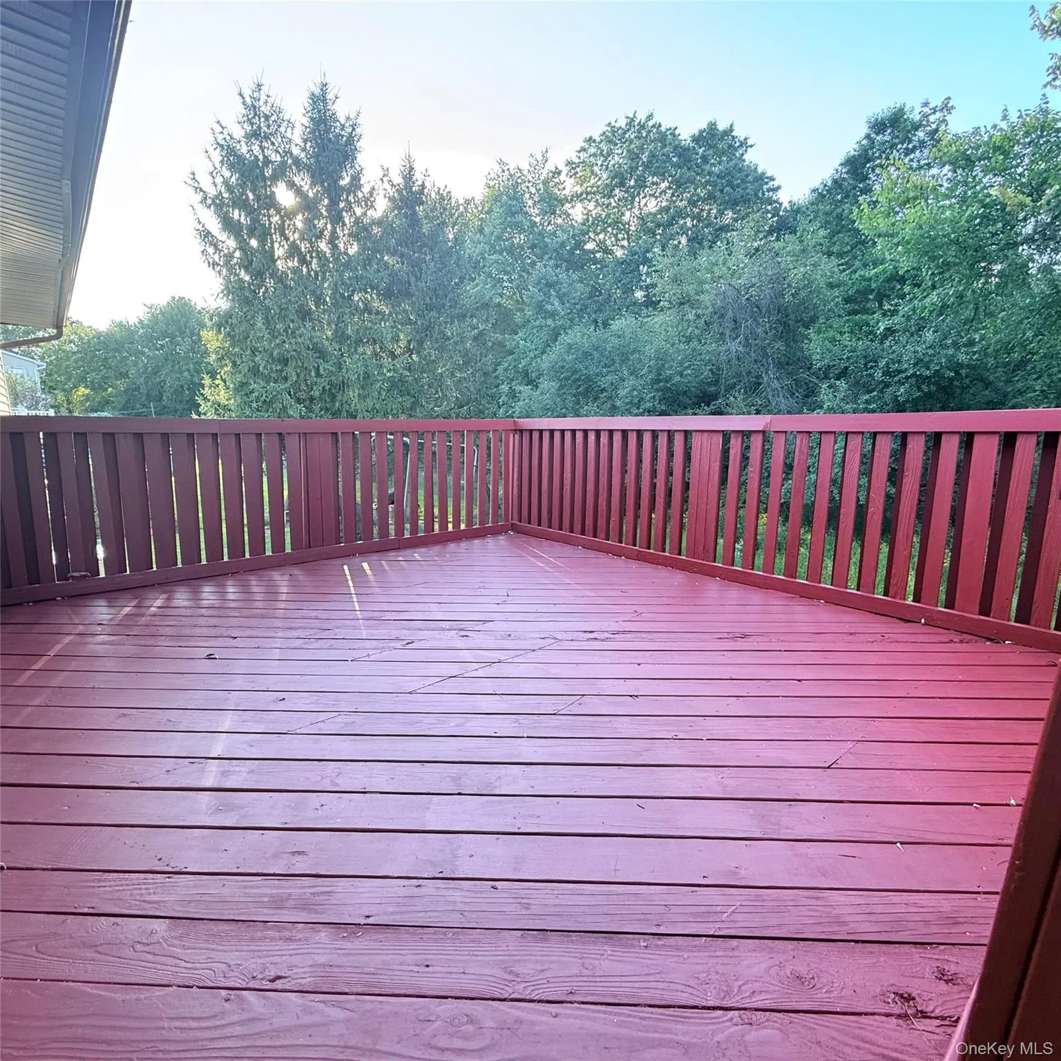 Expansive outdoor deck with red-stained wood flooring and coordinating railings Expansive outdoor deck with red-stained wood flooring and coordinating railings