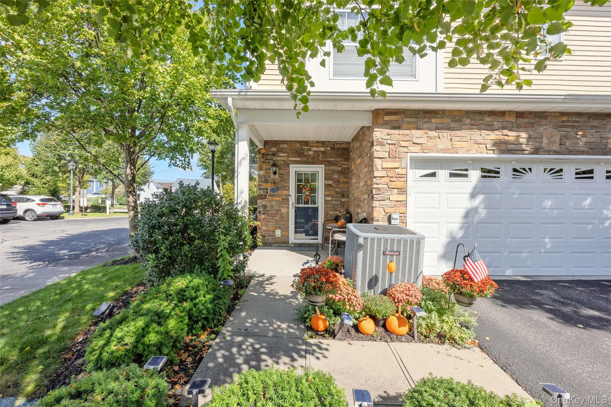 Stone veneer facade with a two-car garage, covered porch entry, and mature landscaping Stone veneer facade with a two-car garage, covered porch entry, and mature landscaping