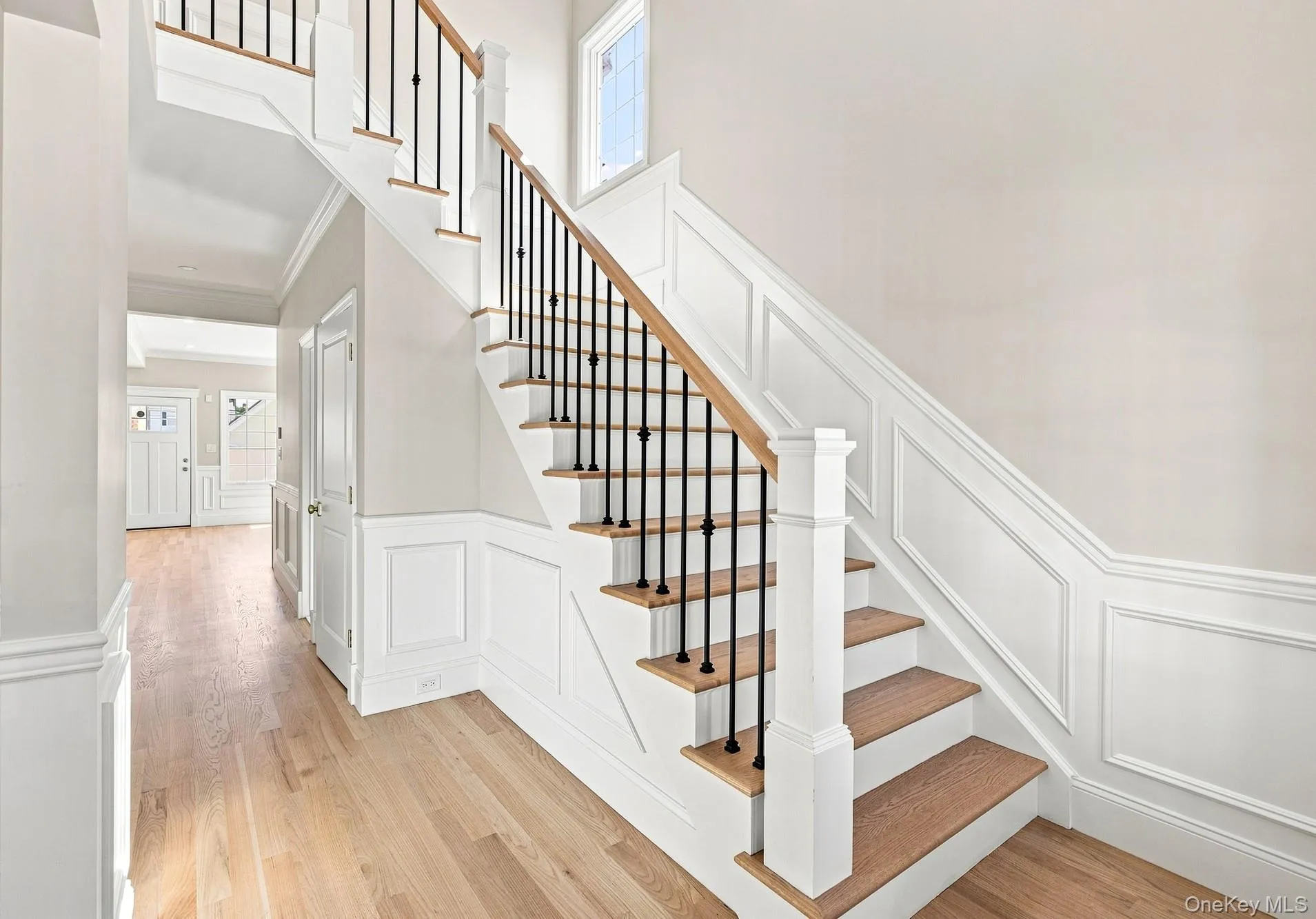 Light and Bright entryway and stairs to second floor Hardwood flooring, wainscoting, solid panel doors, wood-finish stair treads, and wrought iron balusters. Light and Bright entryway and stairs to second floor Hardwood flooring, wainscoting, solid panel doors, wood-finish stair treads, and wrought iron balusters.