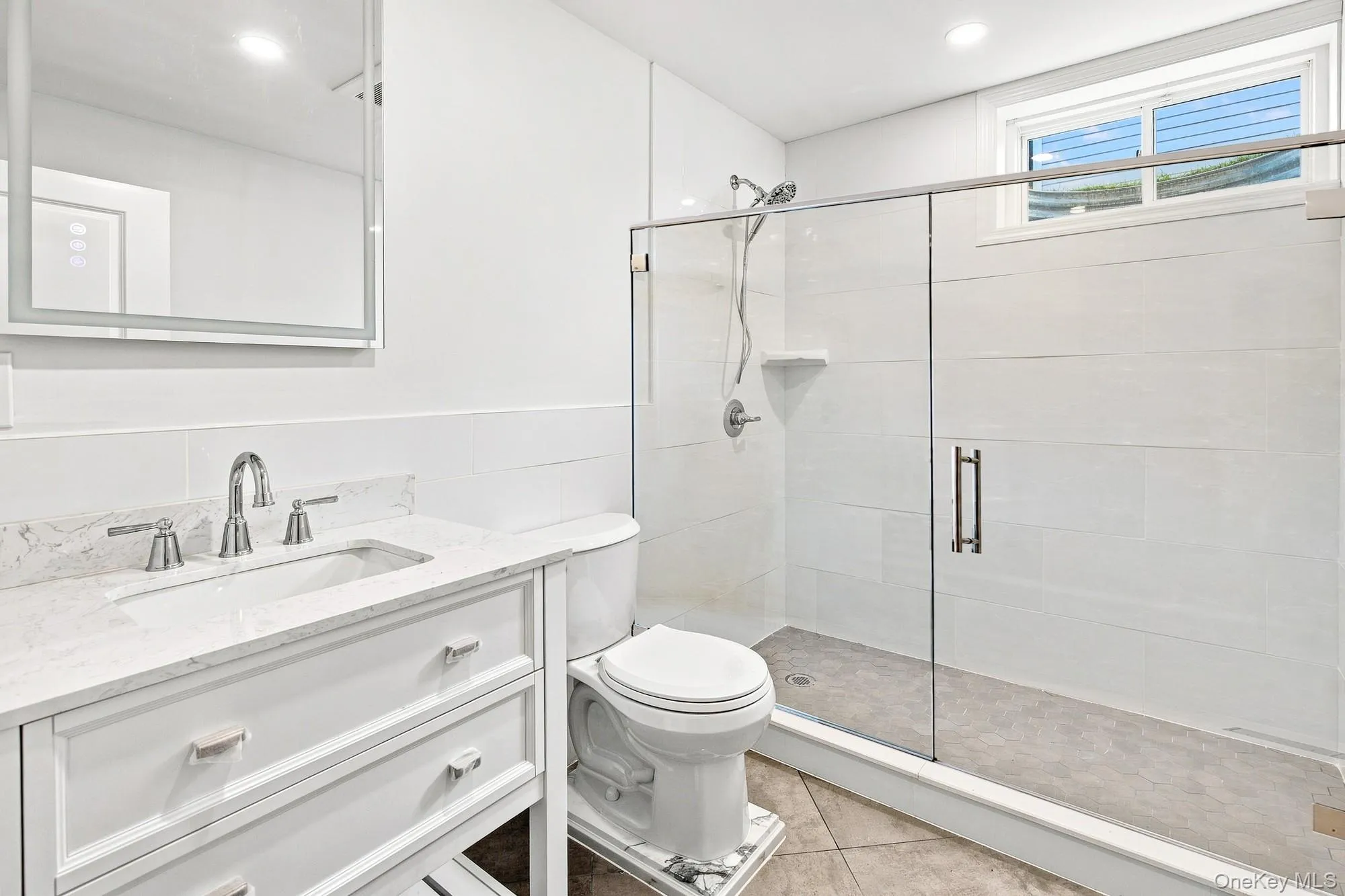 Lower level bath with white vanity with an integrated rectangular sink, chrome fixtures, and white countertop. Lower level bath with white vanity with an integrated rectangular sink, chrome fixtures, and white countertop.
