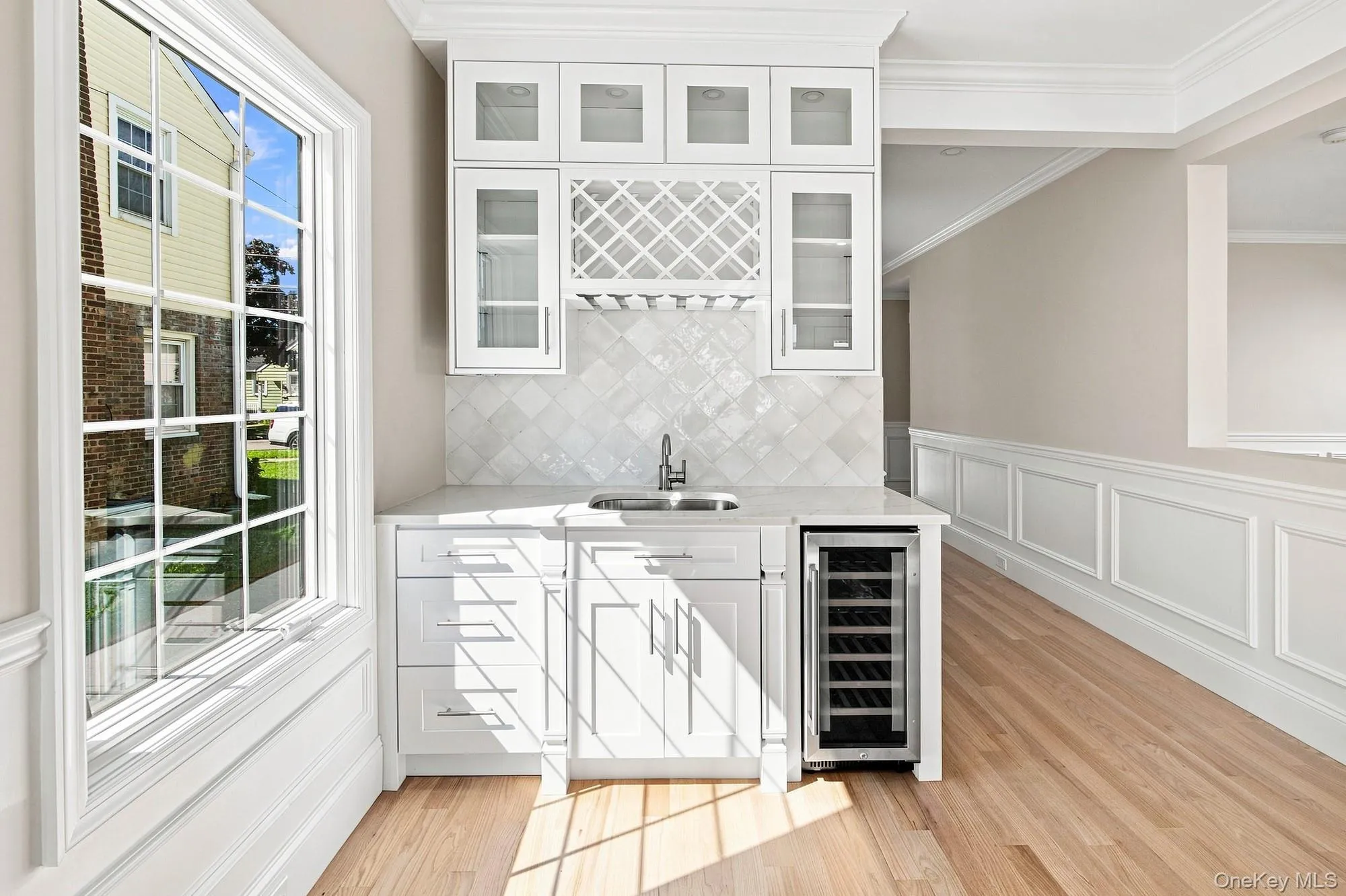 Built-in beverage station featuring white cabinetry, a wine rack, and a beverage cooler. Built-in beverage station featuring white cabinetry, a wine rack, and a beverage cooler.