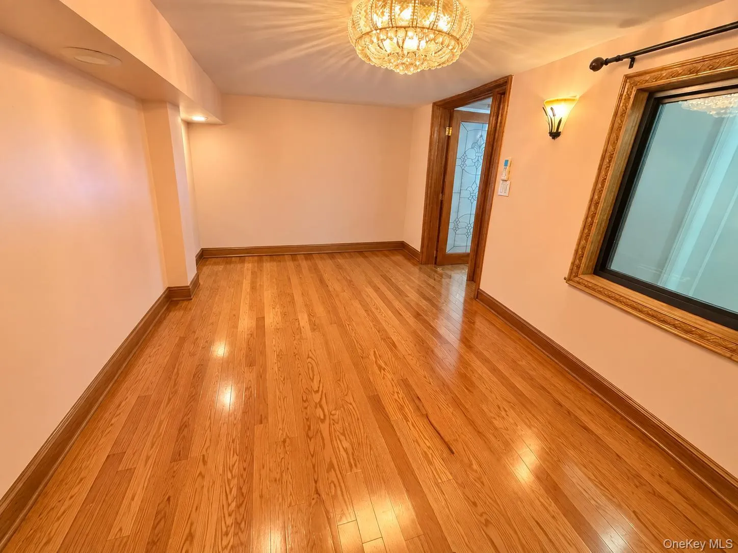 Hardwood flooring, ornate chandelier, recessed lighting, wall sconce, and framed window Hardwood flooring, ornate chandelier, recessed lighting, wall sconce, and framed window