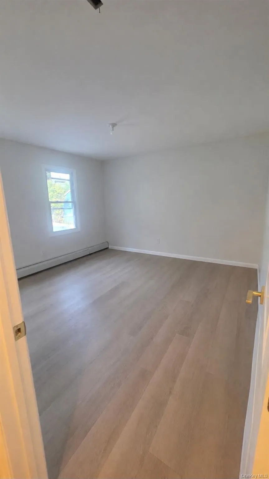 Wood-finish flooring, white walls, single window, white trim, and a gold-tone door handle Wood-finish flooring, white walls, single window, white trim, and a gold-tone door handle