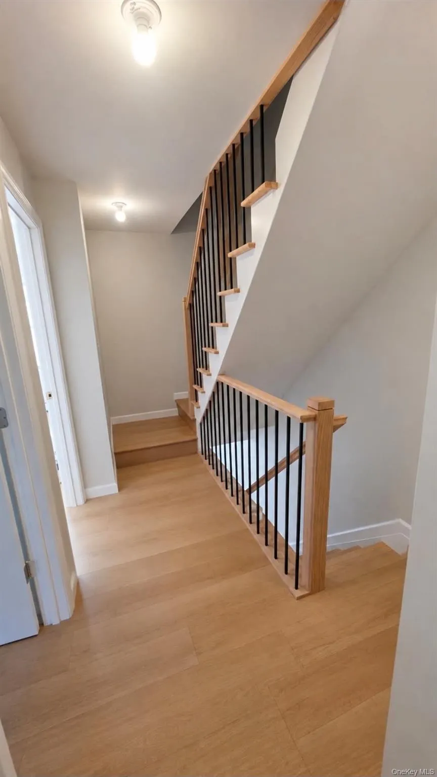 Wood-finish flooring throughout, with a staircase featuring wood handrails and black metal balusters Wood-finish flooring throughout, with a staircase featuring wood handrails and black metal balusters