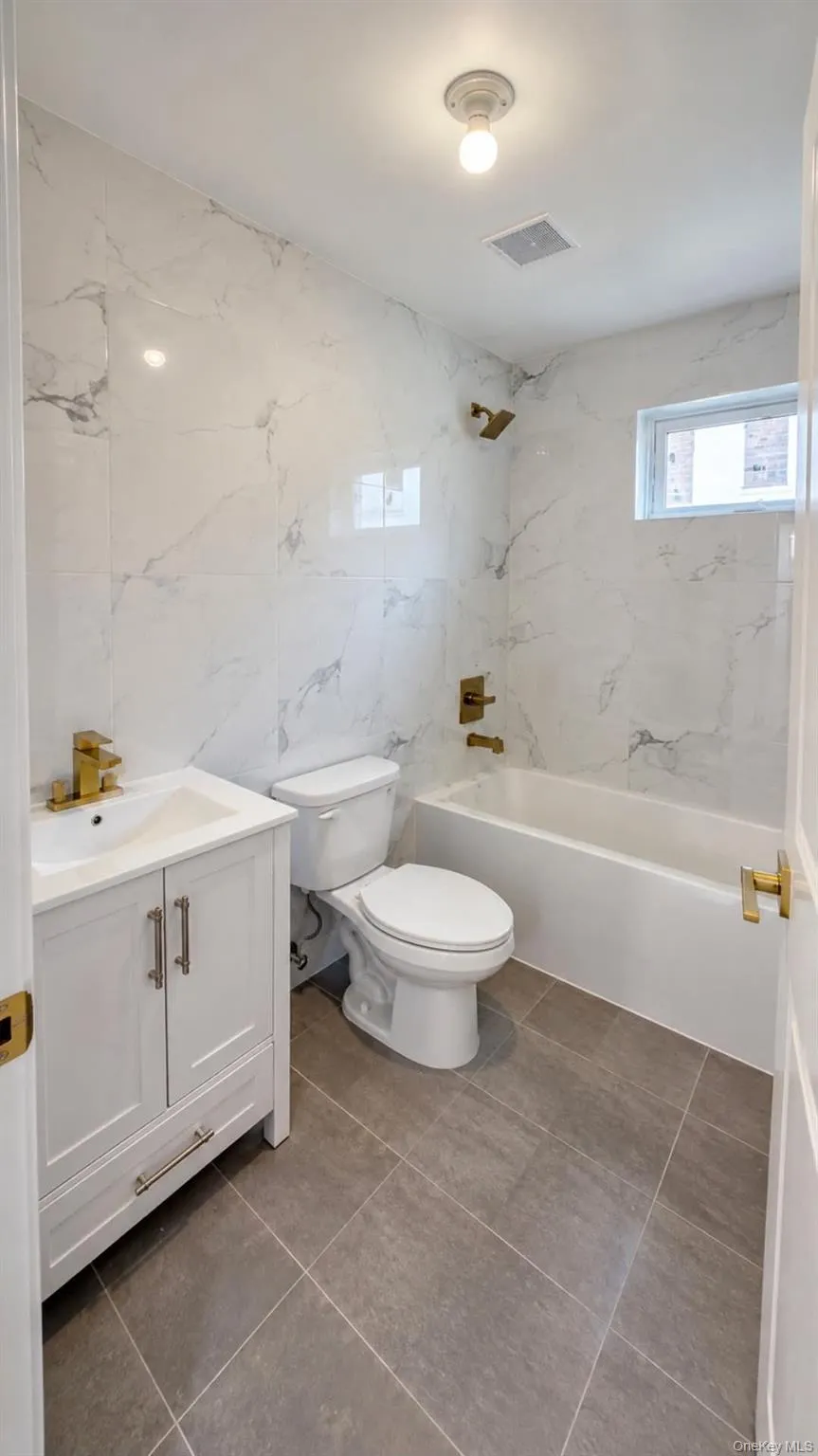 White vanity with gold-finish faucet, white toilet, and a white bathtub with gold-finish fixtures White vanity with gold-finish faucet, white toilet, and a white bathtub with gold-finish fixtures