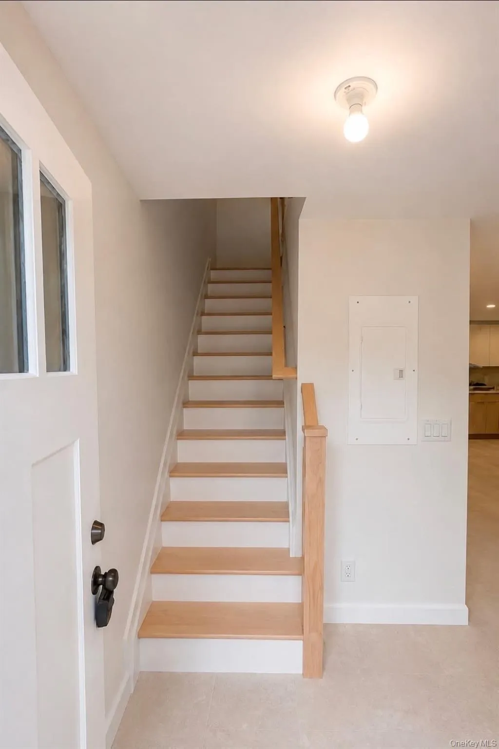 Entryway with wood-finish stairs, white risers, and natural wood handrail Entryway with wood-finish stairs, white risers, and natural wood handrail
