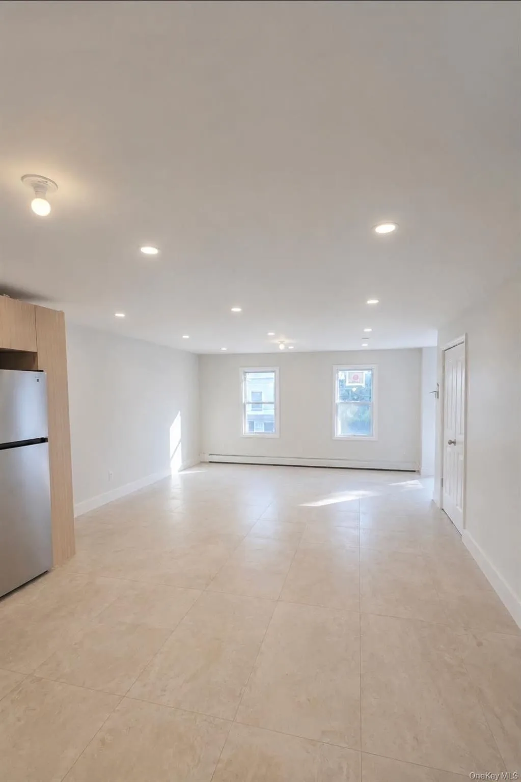 Recessed lighting, tile flooring, light wood-finish cabinetry, stainless steel refrigerator, and multiple windows Recessed lighting, tile flooring, light wood-finish cabinetry, stainless steel refrigerator, and multiple windows