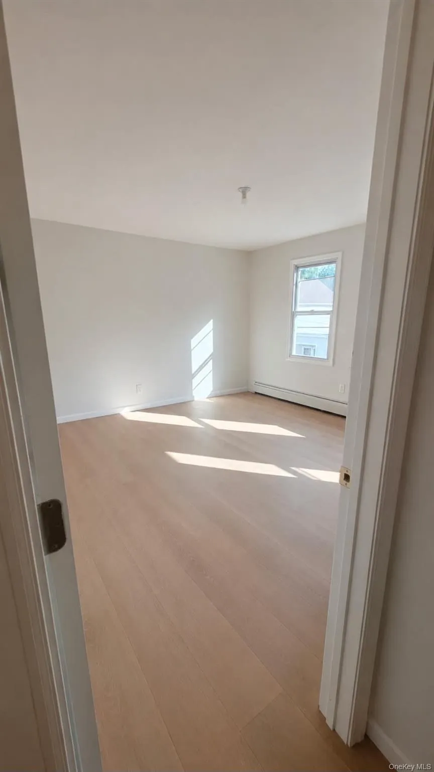 Room featuring light wood-finish flooring, white walls, and a window Room featuring light wood-finish flooring, white walls, and a window