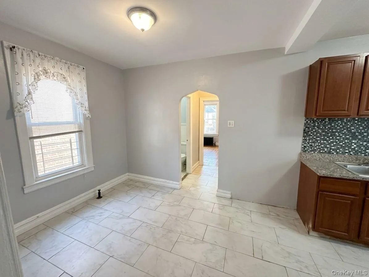 Tile flooring, recessed lighting, wood-finish cabinetry, mosaic tile backsplash, and a double-basin sink Tile flooring, recessed lighting, wood-finish cabinetry, mosaic tile backsplash, and a double-basin sink