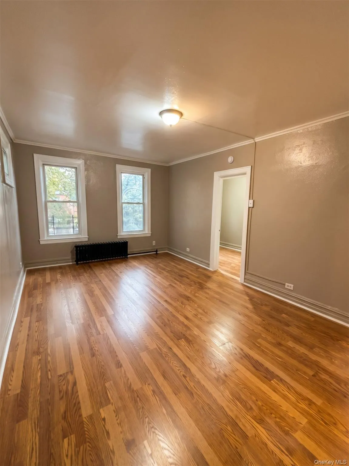 Hardwood flooring, crown molding, two windows, and a flush mount ceiling light fixture Hardwood flooring, crown molding, two windows, and a flush mount ceiling light fixture