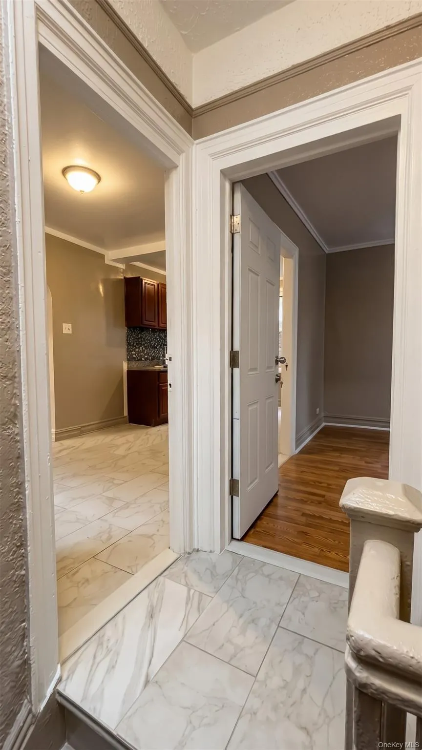 Tiled entry with white door trim, overhead lighting, and a white paneled door Tiled entry with white door trim, overhead lighting, and a white paneled door