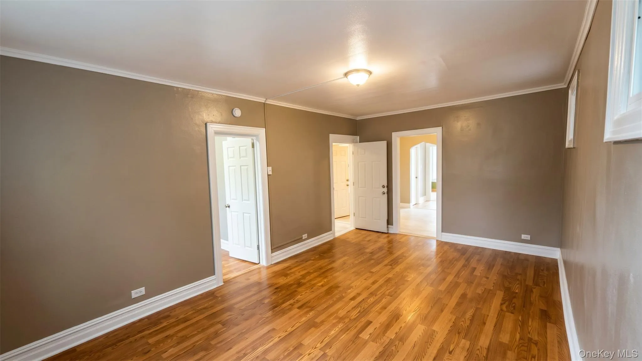 Hardwood flooring, crown molding, two windows, and a flush mount ceiling light fixture Hardwood flooring, crown molding, two windows, and a flush mount ceiling light fixture