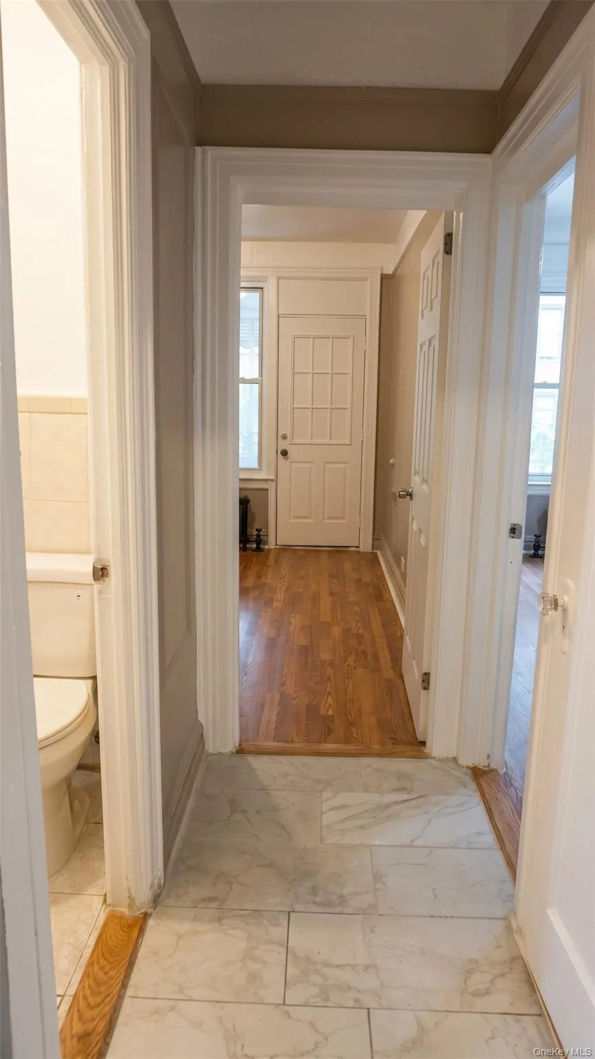 Tiled flooring with wood-finish trim leading to a separate room with wood-finish flooring Tiled flooring with wood-finish trim leading to a separate room with wood-finish flooring