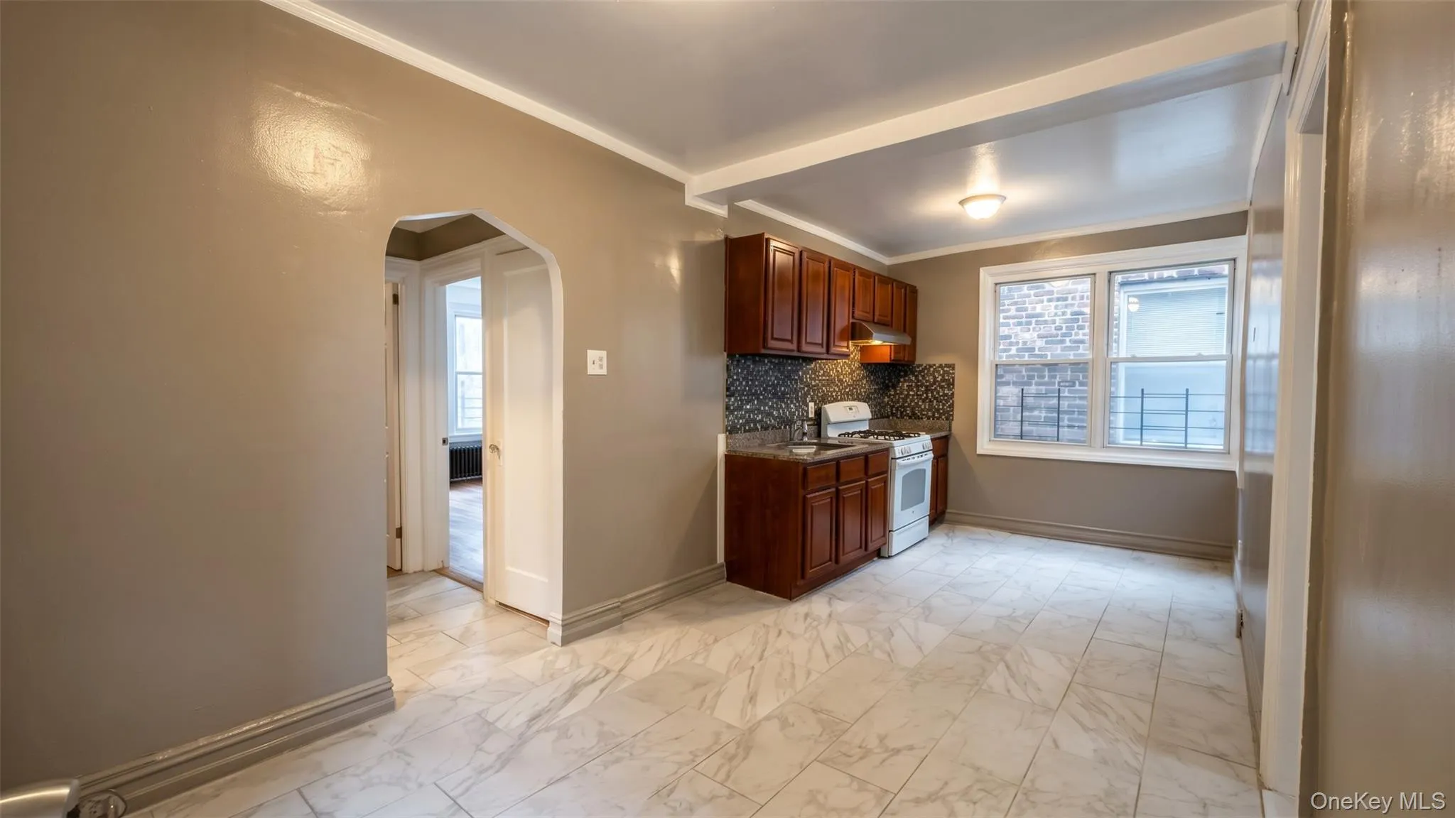 Kitchen featuring wood-finish cabinetry, mosaic tile backsplash, granite-style countertops, and a double-pane window Kitchen featuring wood-finish cabinetry, mosaic tile backsplash, granite-style countertops, and a double-pane window