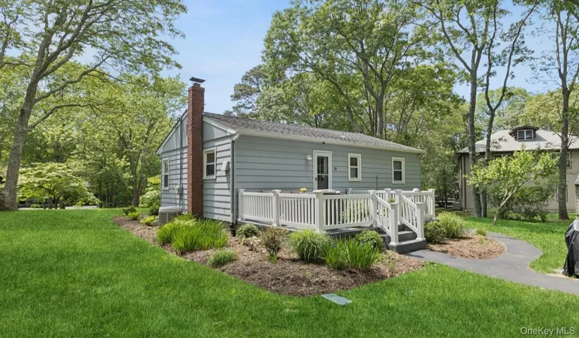 Rear view of house featuring a chimney, a yard, a wooden deck, and cooling unit