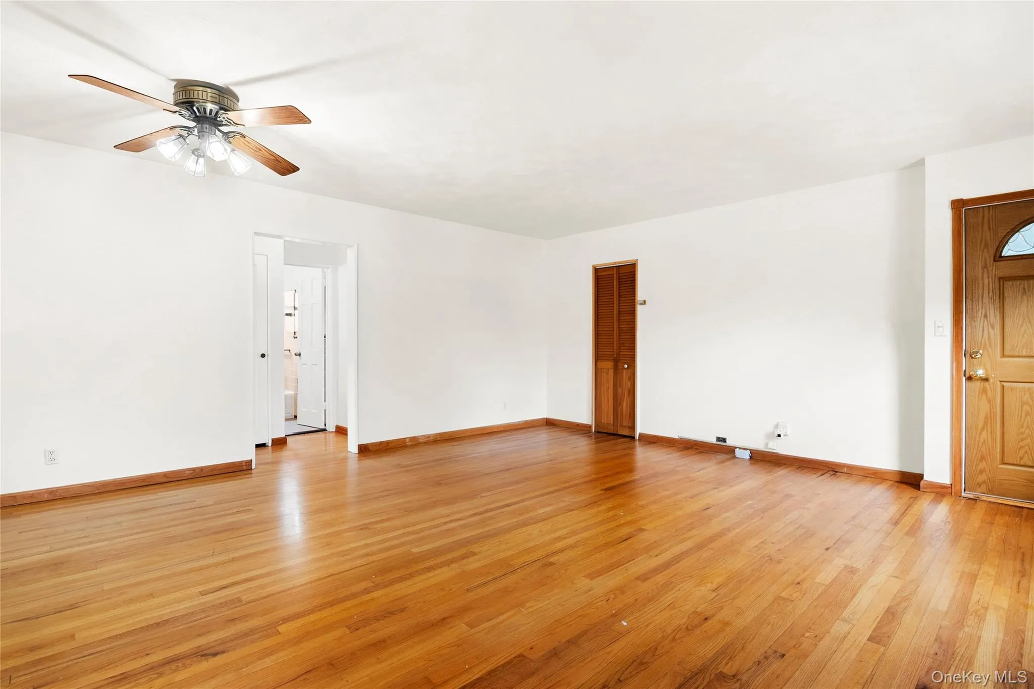 Hardwood flooring, white walls, wood-finish interior doors, recessed entry door, and a ceiling fan with integrated lighting.Closet with ample storage space Hardwood flooring, white walls, wood-finish interior doors, recessed entry door, and a ceiling fan with integrated lighting.Closet with ample storage space