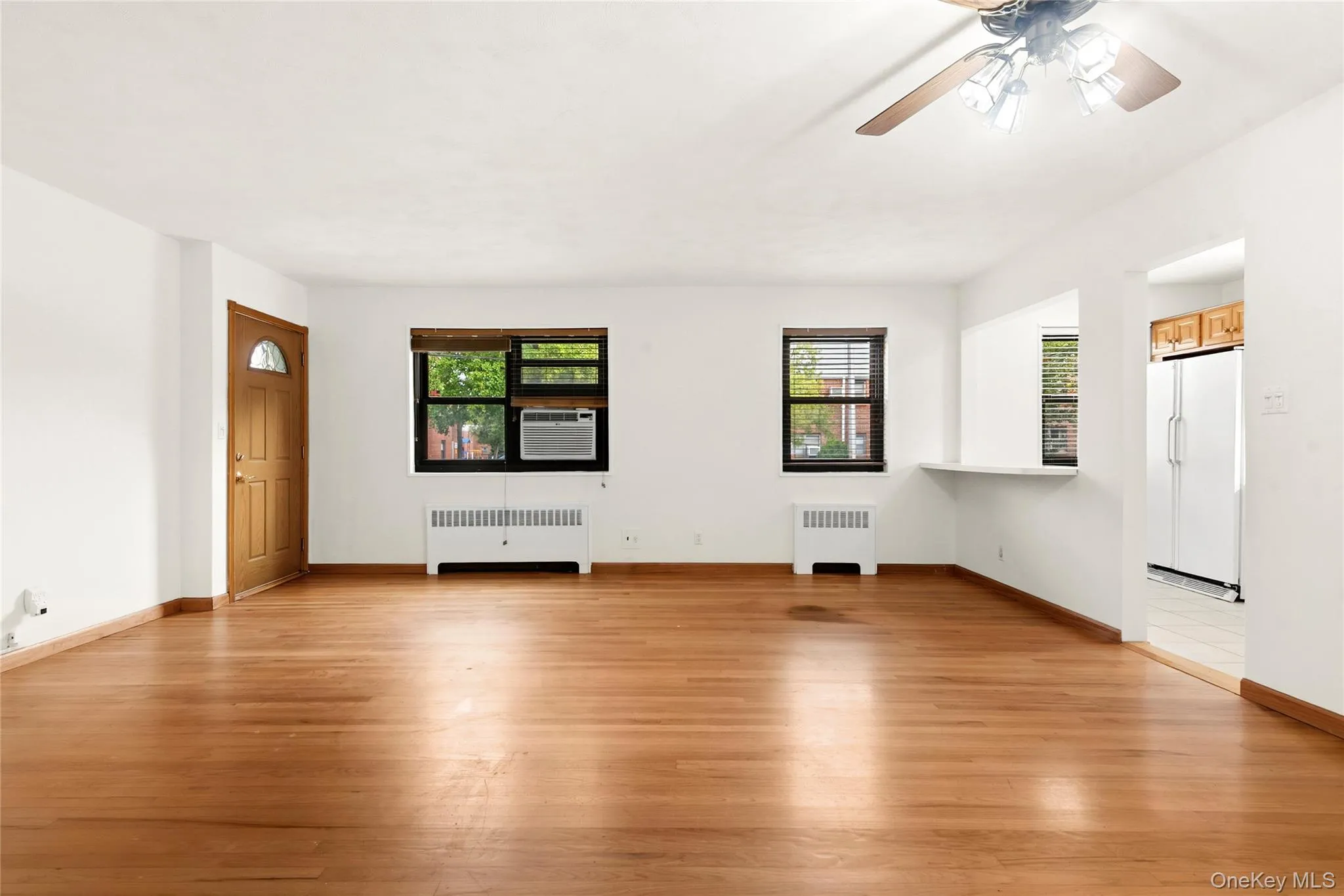 Hardwood flooring, painted white walls, recessed window treatments, ceiling fan with integrated lighting, and a pass-through counter Hardwood flooring, painted white walls, recessed window treatments, ceiling fan with integrated lighting, and a pass-through counter