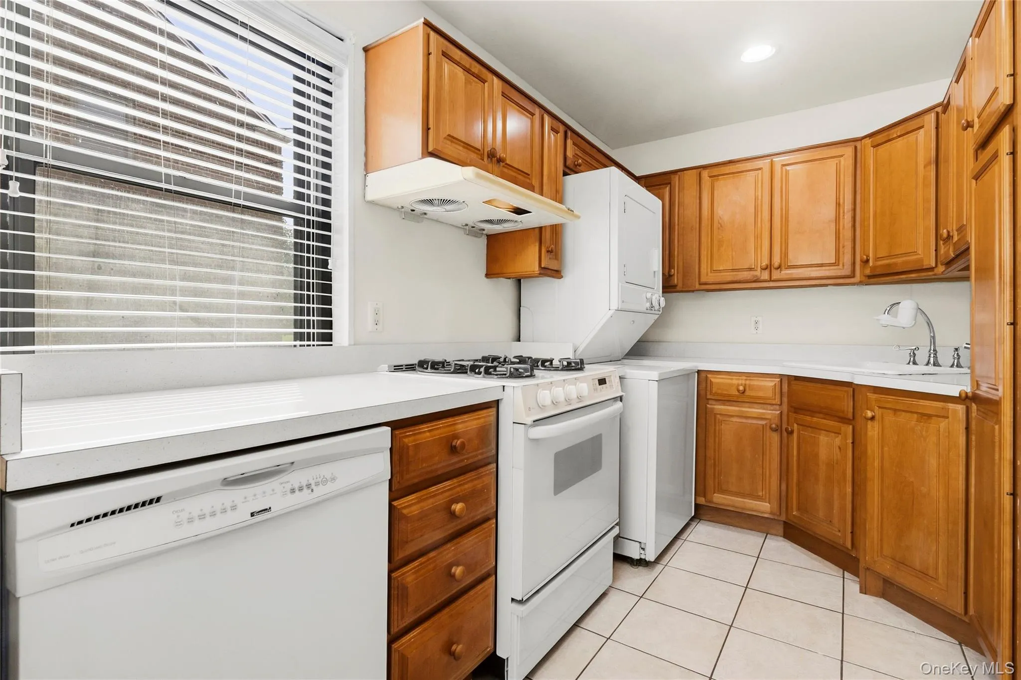 Kitchen featuring wood-finish cabinetry, white countertops, a gas range, white dishwasher, and tiled flooring Kitchen featuring wood-finish cabinetry, white countertops, a gas range, white dishwasher, and tiled flooring