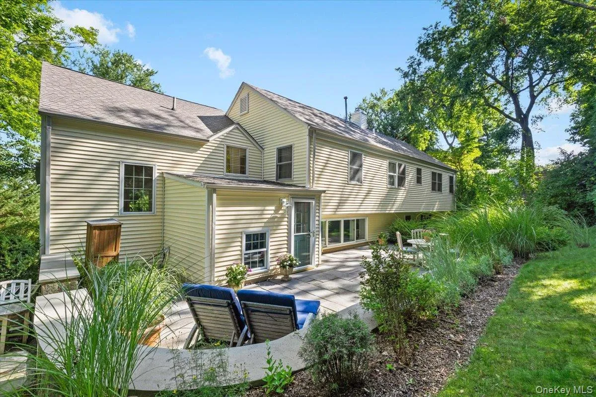 Exterior siding with multiple windows, paver patio, and surrounding landscaping Exterior siding with multiple windows, paver patio, and surrounding landscaping