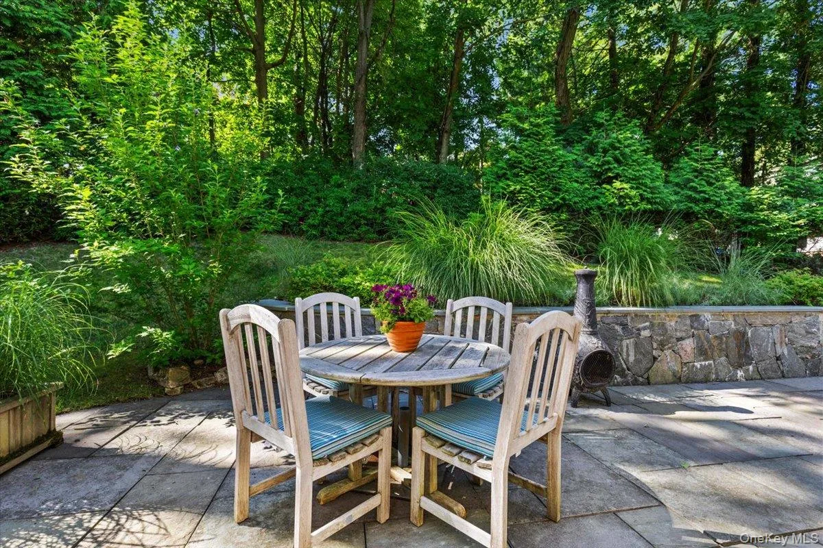 Outdoor patio featuring natural stone, a stone retaining wall, and lush greenery Outdoor patio featuring natural stone, a stone retaining wall, and lush greenery