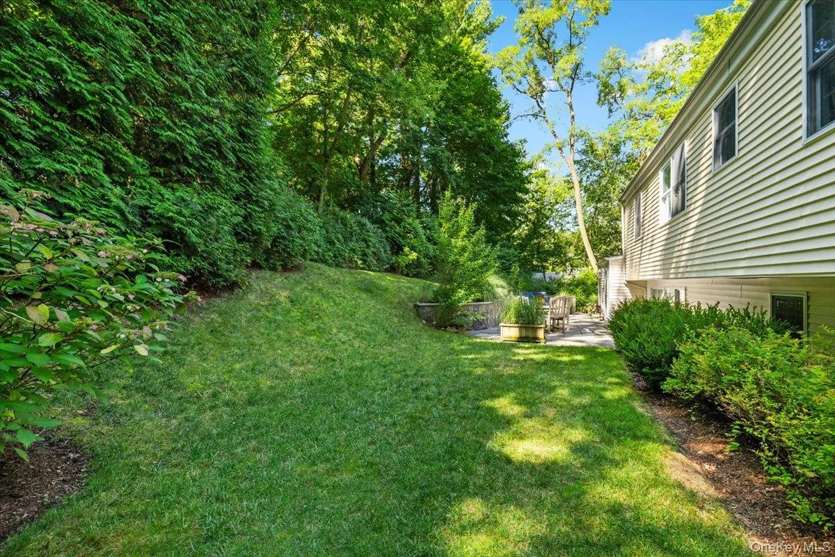 Expansive lawn with mature perimeter plantings and a stone patio for entertaining and play area Expansive lawn with mature perimeter plantings and a stone patio for entertaining and play area