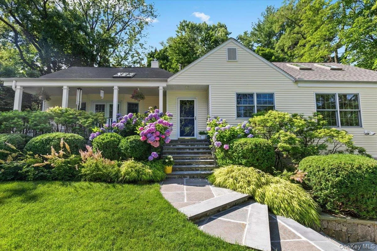 Entryway with stone steps, a covered porch, and extensive landscaping. Showing expanse of home including addition Entryway with stone steps, a covered porch, and extensive landscaping. Showing expanse of home including addition
